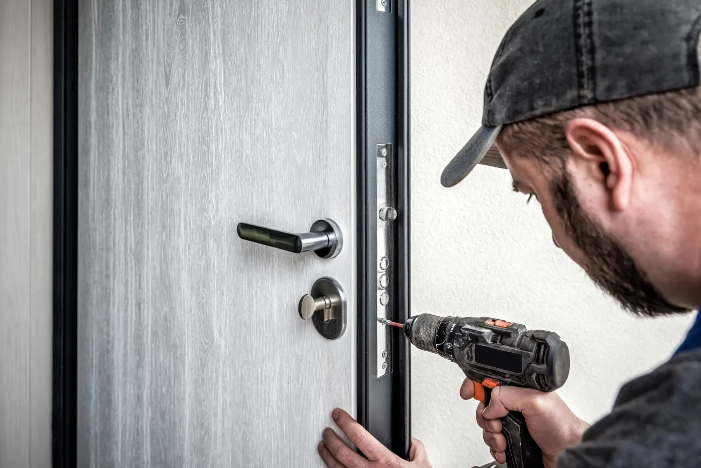 Serrurier au travail sur une porte de hall d'immeuble faubourien du 10e arrondissement de Paris (75010)