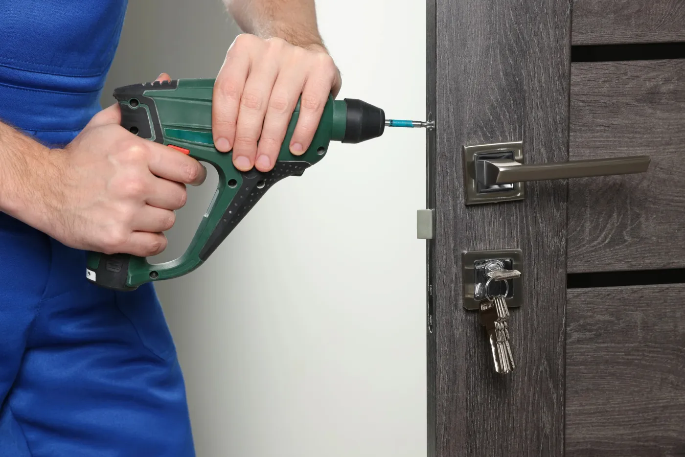 Serrurier fixant une serrure de sûreté sur une porte de rapport d'un immeuble faubourien du 10e